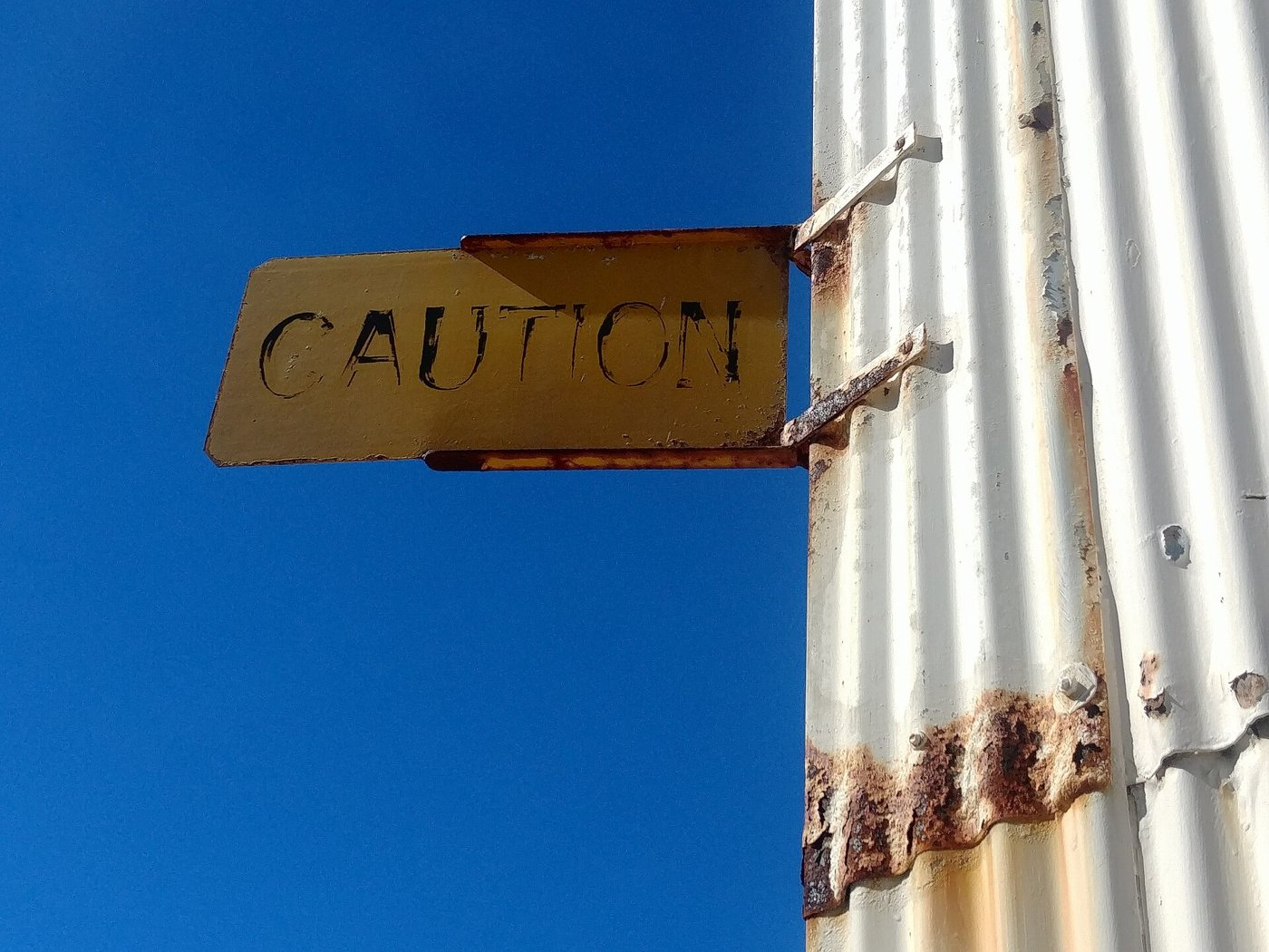 固定在墙面上的黄色 CAUTION 警告牌