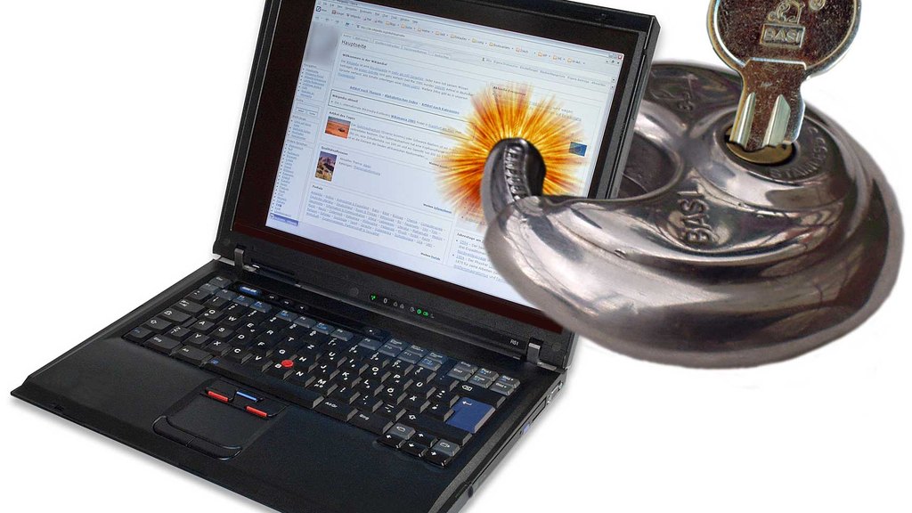 黑色笔记本电脑（ThinkPad 外形）旁边放着一把挂锁