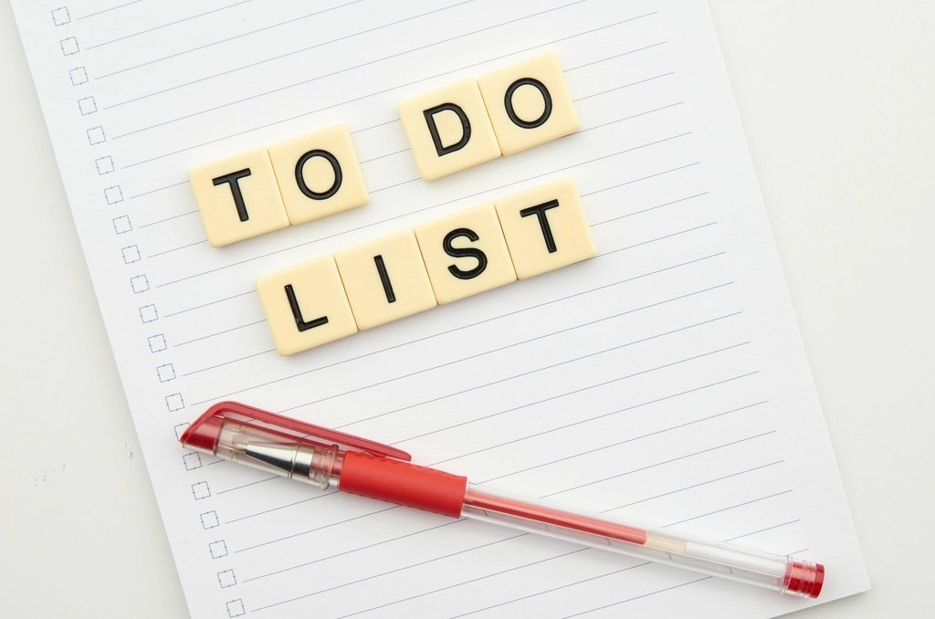 横线笔记本上写着 TO DO LIST，旁边放着一支红色圆珠笔