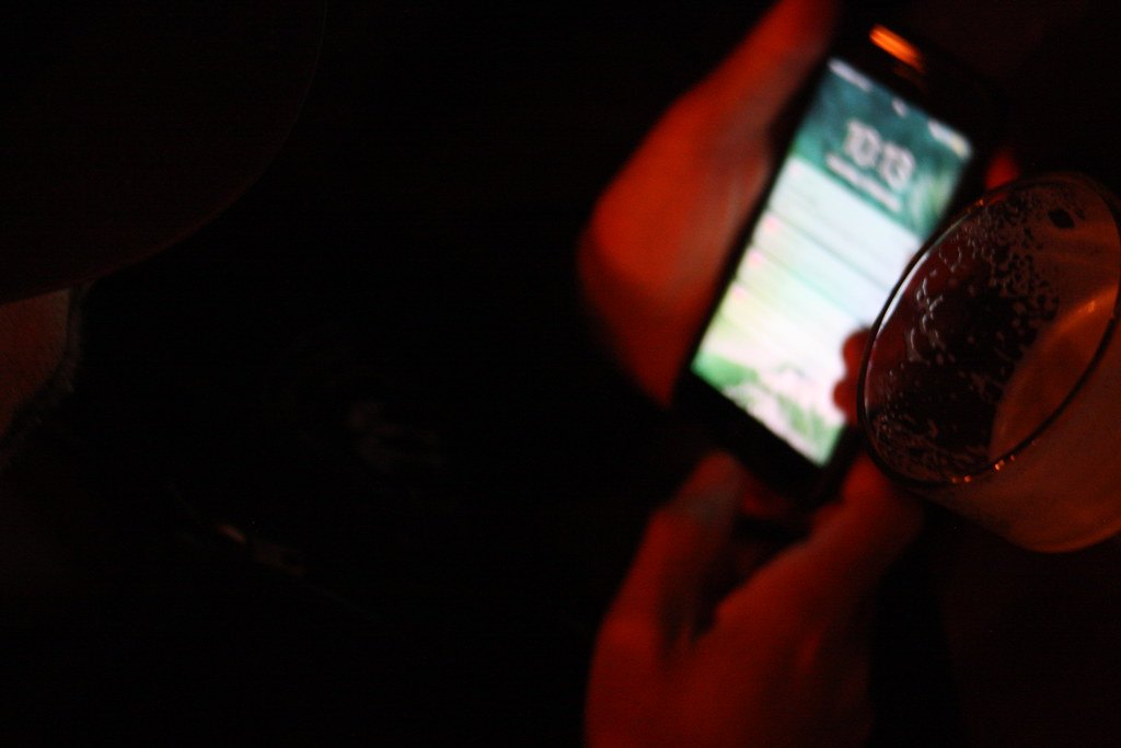 夜里,一个人握着亮屏的手机,桌上搁着一只玻璃杯